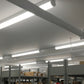 Linkable LED linear strip light fixtures illuminating a warehouse workspace
