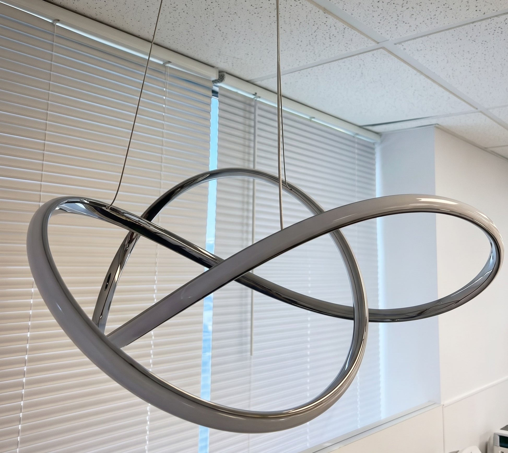 Close-up of modern LED swirl chandelier showing aluminum frame and frosted diffuser detail
