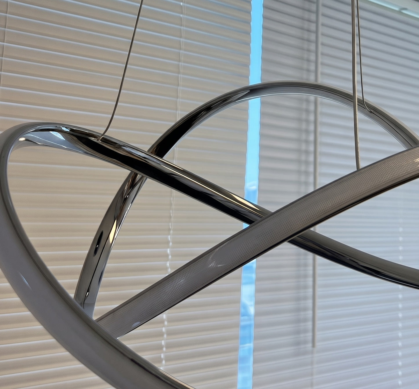 Close-up of modern LED swirl chandelier showing the sculptural swirl design and frosted diffuser when off