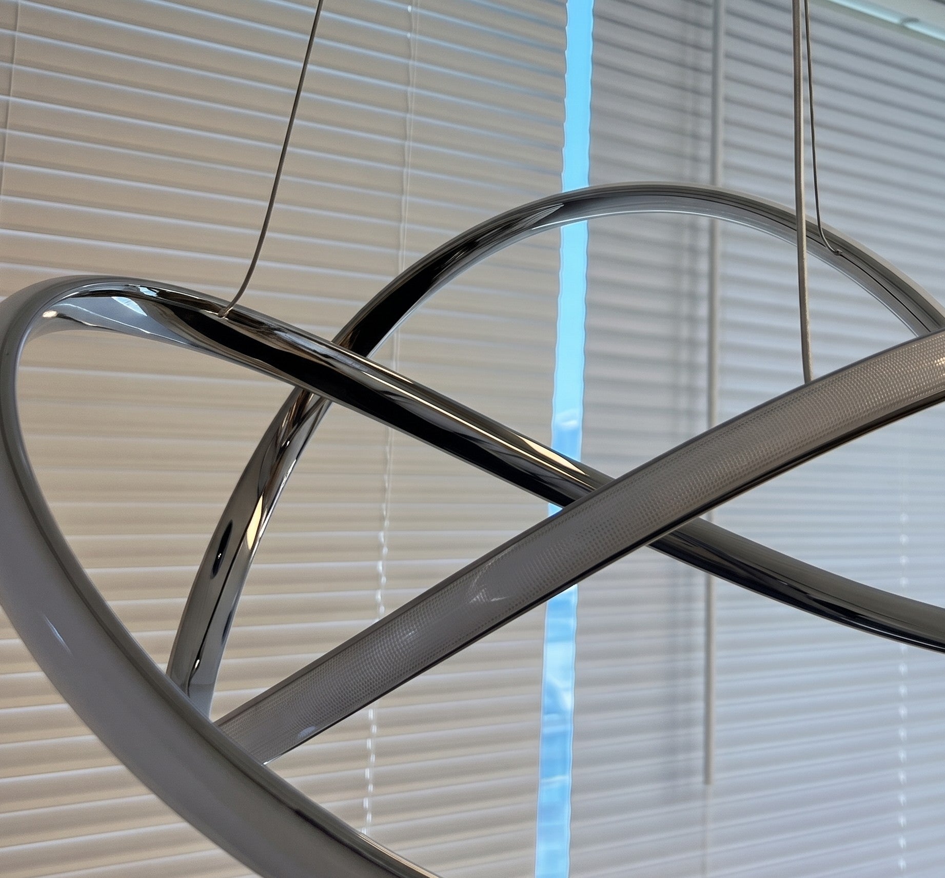 Close-up of modern LED swirl chandelier showing the sculptural swirl design and frosted diffuser when off